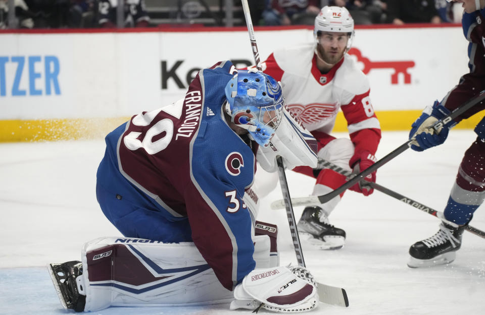 Colorado Avalanche goaltender Pavel Francouz, left, covers the puck with his glove as Detroit Red Wings defenseman Jordan Oesterle, center, drives to the net in the second period of an NHL hockey game Monday, Jan. 16, 2023, in Denver. (AP Photo/David Zalubowski)