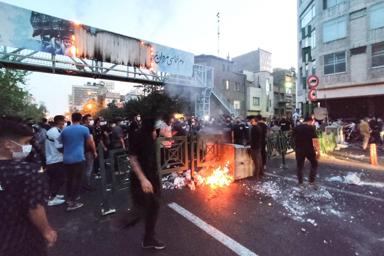 A picture obtained by AFP outside Iran on September 21, 2022, shows Iranian demonstrators burning a rubbish bin in the capital Tehran during a protest for Mahsa Amini, days after she died in police custody. - Protests spread to 15 cities across Iran overnight over the death of the young woman Mahsa Amini after her arrest by the country's morality police, state media reported today.In the fifth night of street rallies, police used tear gas and made arrests to disperse crowds of up to 1,000 people, the official IRNA news agency said.