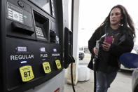 Heatherlee Madden puts the nozzle back after getting gas for 98.9 cents a gallon, Monday, March 30, 2020, in Cleveland. Oil started the year above $60 and has plunged on expectations that a weakened economy will burn less fuel. The world is awash in oil, meanwhile, as producers continue to pull more of it out of the ground. (AP Photo/Tony Dejak)