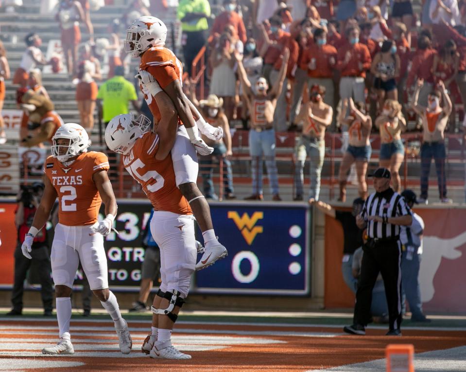 Texas offensive lineman Junior Angilau lifts Brennan Eagles after the wide receiver's touchdown catch against West Virginia in 2020. The veteran right guard is excited about the team's incoming flood of offensive line talent but suggested this week that redshirting is always a good idea for those playing up front.