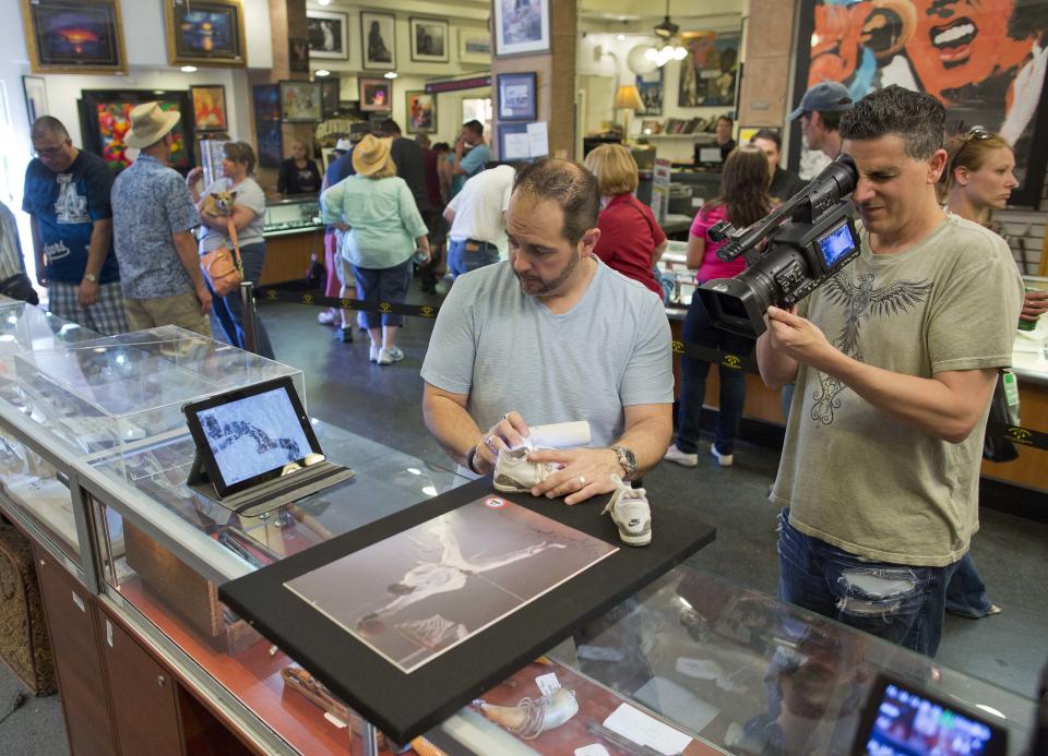 In this Wednesday, April 3, 2013, photo, cameraman Joe Murgia, right, shoots a close-up of Michael Jordan memorabilia which was brought in to the Gold & Silver Pawn shop for an episode of the reality tv series Pawn Stars, in Las Vegas. Pawn sales at the shop, which is featured in the television reality show Pawn Stars, bring in about $20 million a year, up from the $4 million a year it made before the show aired. Turning small business owners into stars has become a winning formula for television producers, but the businesses featured in the shows are cashing in, too. Sales explode after just a few episodes have aired, transforming nearly unknown small businesses into household names. (AP Photo/Julie Jacobson)
