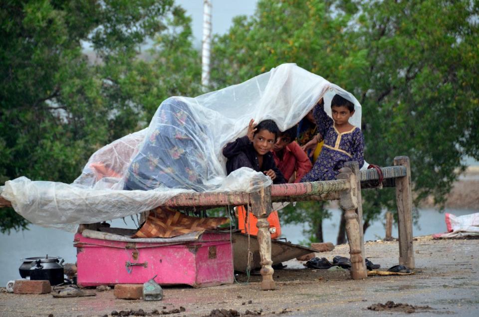 A displaced family takes refuge on a roadside after fleeing their flood-hit home in Jaffarabad, Baluchistan province, on Wednesday (AP)