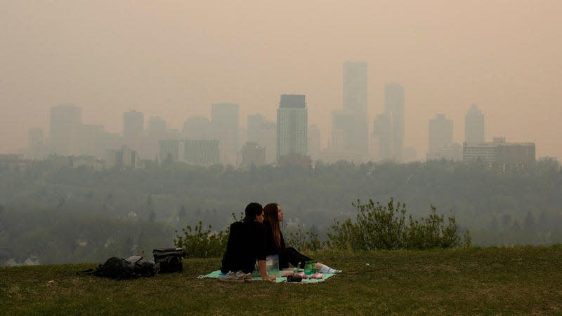 Smoke from wildfires blankets the city as a couple has a picnic in Edmonton, Alberta on May 11, 2024. - Photo: Jason Franson/The Canadian Press (AP)