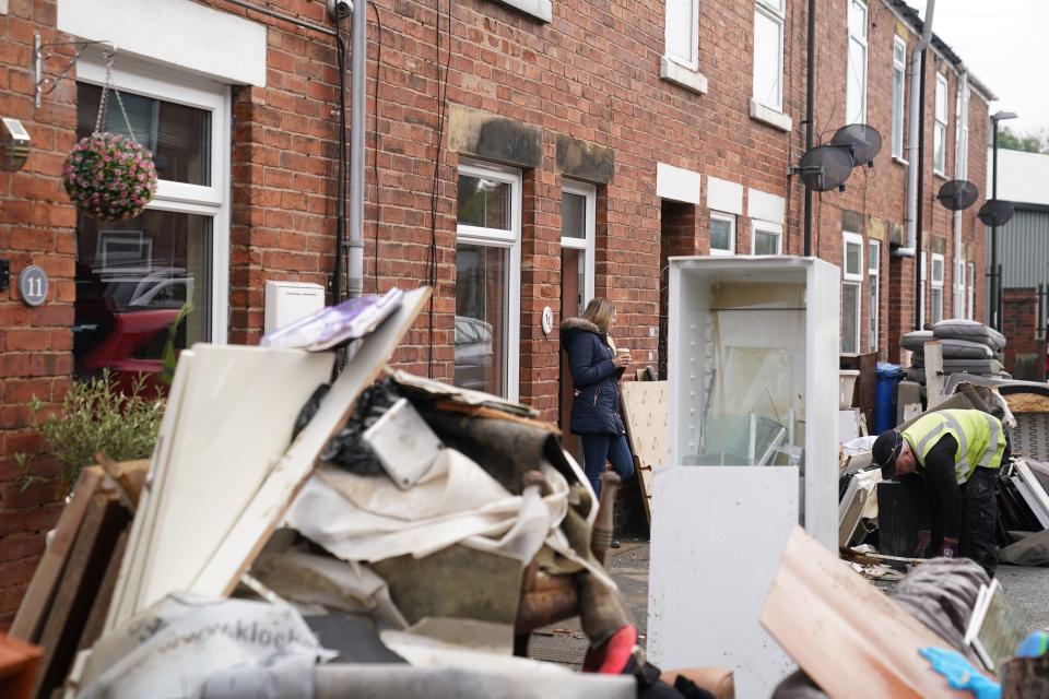 A resident looks at a local authority worker collecting damaged furniture from outside a property on Sherwood Street in Chesterfield, as the clean up began in the aftermath of Storm Babet (PA Wire)