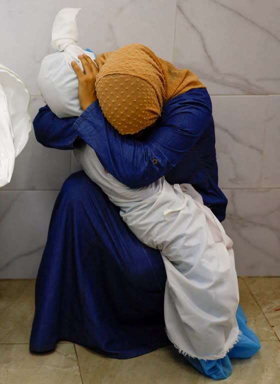 A woman embraces the body of a Palestinian child killed in Israeli strikes, at a hospital in Khan Younis in the southern Gaza Strip, Oct. 17.<span class="copyright">Mohammed Salem—Reuters</span>