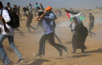 Tear gas canisters are fired by Israeli troops towards Palestinian demonstrators as they run during a protest demanding the right to return to their homeland at the Israel-Gaza border, in the southern Gaza Strip August 17, 2018. REUTERS/Ibraheem Abu Mustafa