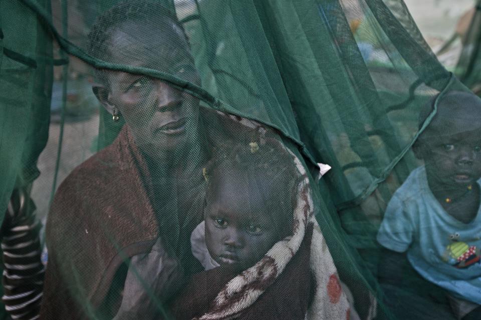 FILE - In this Thursday, Jan. 2, 2014 file photo, one of the few to have a mosquito net, a displaced family who fled the recent fighting between government and rebel forces in Bor by boat across the White Nile, sit under it after waking up in the morning in the town of Awerial, South Sudan. Sub-Saharan Africa has seen a very violent start to 2014 with raging conflicts in South Sudan and Central African Republic - the death tolls are huge and the individual incidents gruesome, with one estimate saying nearly 10,000 have been killed in South Sudan in a month of warfare. (AP Photo/Ben Curtis, File)