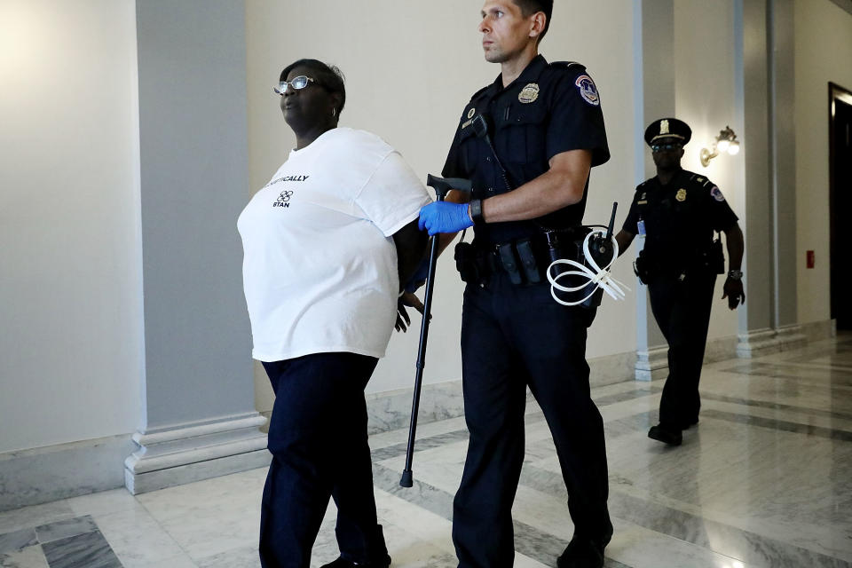 A U.S. Capitol Police officer carries a woman's cane after arresting her for protesting against the Republican health care repeal and replace legislation outside the offices of Sen. John Kennedy (R-La.) on July 19, 2017, in Washington, D.C.<br /><br /><i>Warning: The following photo contains nudity.</i>