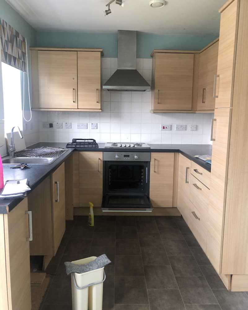 Pre-renovated white and blue kitchen with light wood finish cabinets and brown tile flooring