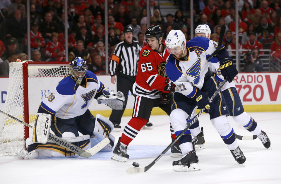 St. Louis Blues defenseman Alex Pietrangelo (27) clears the puck away from the net and Chicago Blackhawks center Andrew Shaw (65) as goalie Ryan Miller defends during the second period in Game 3 of a first-round NHL hockey Stanley Cup playoff series game Monday, April 21, 2014, in Chicago. (AP Photo/Charles Rex Arbogast)