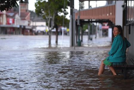 A local resident watches as floodwaters enter the main street of northern New South Wales town of Lismore, Australia, March 31, 2017 after heavy rains associated with Cyclone Debbie swelled rivers to record heights across the region. AAP/Dave Hunt/via REUTERS