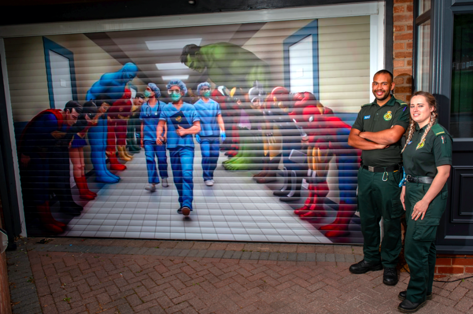 Paramedic Aaron Duncan and Technician Kim Haynes look at the art work paying tribute to NHS workers on Craig Perkins' garage door. (SWNS)