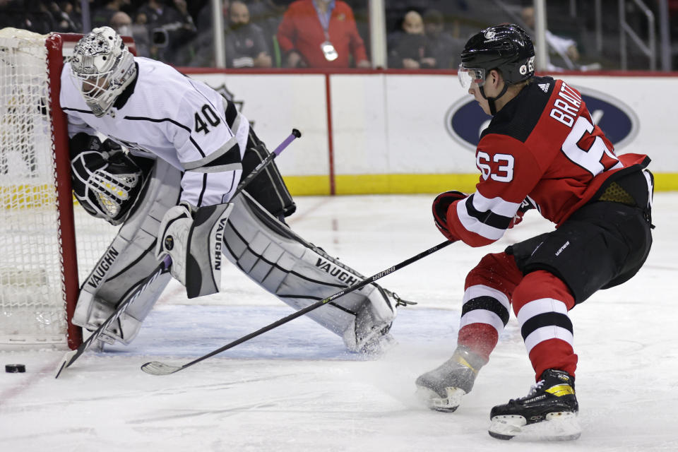 Los Angeles Kings goaltender Cal Petersen clears the puck in front of New Jersey Devils left wing Jesper Bratt (63) during the second period of an NHL hockey game Sunday, Jan. 23, 2022, in Newark, N.J. (AP Photo/Adam Hunger)