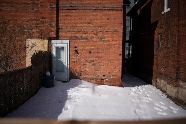 The backyard of 104 has footprints while the back door of 102 Wellington Street North is boarded up.