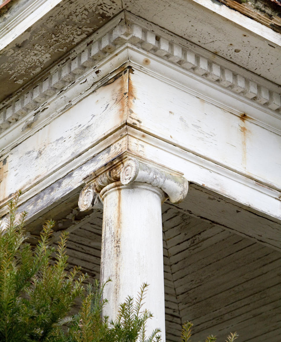 Close-up of a weathered white classical column with decorative capital, part of an old building's architecture