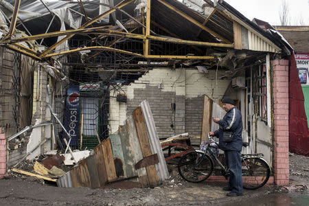 A man checks his mobile phone in front of his destroyed house in the town of Debaltseve, north-east from Donetsk, March 13, 2015. REUTERS/Marko Djurica