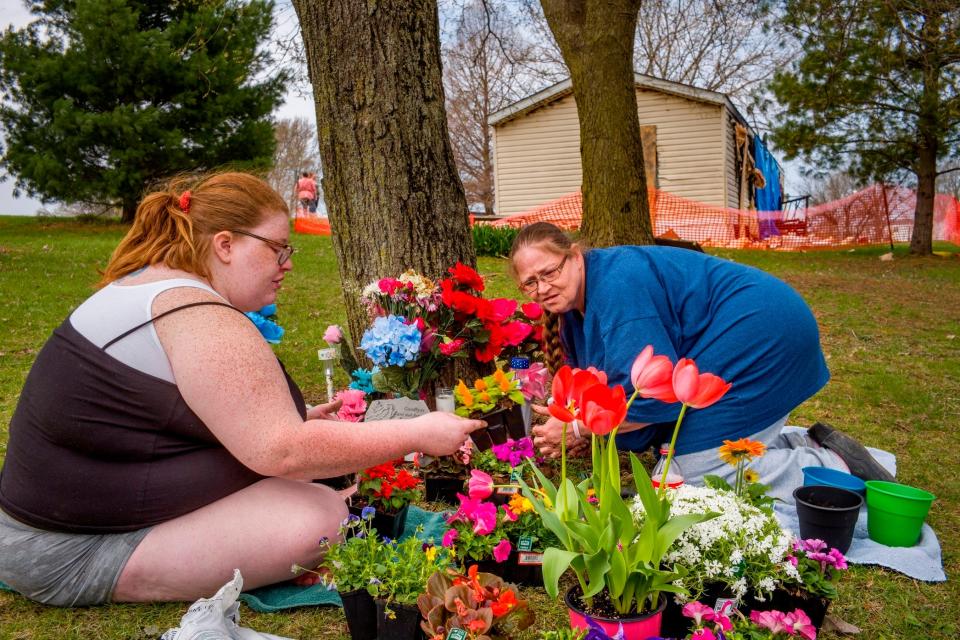 Katie Alwood, left, and her mother, Lori Alwood, plant flowers April 17, 2019 near the Goodfield mobile home, in background, where five relatives died in an April 6 fire.