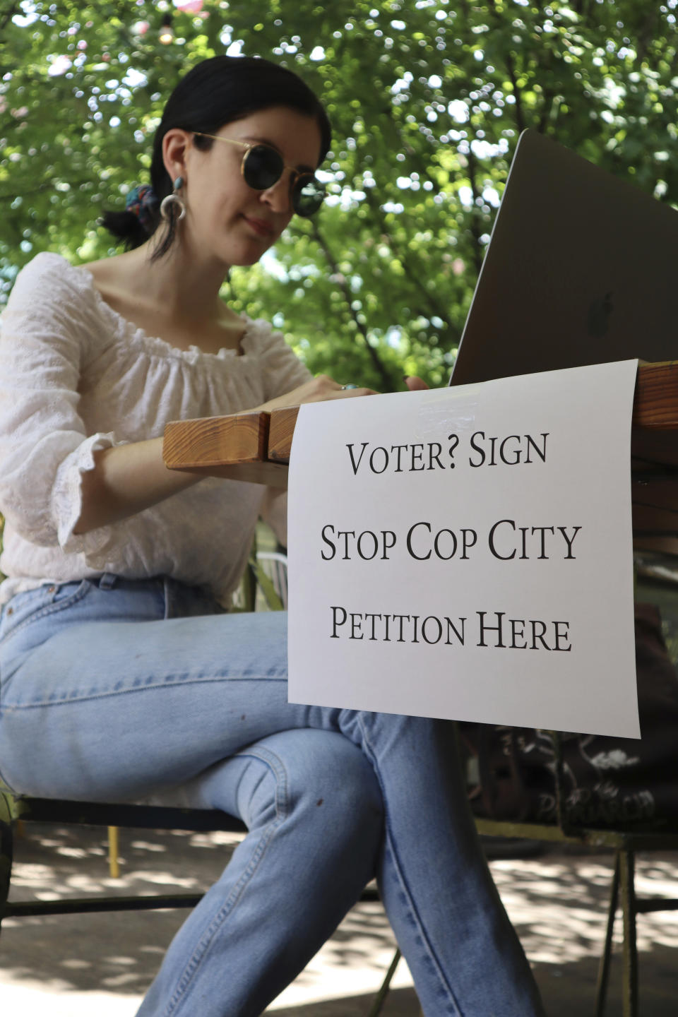 Activist Hannah Riley works on her laptop at Muchacho, a local taco restaurant, while gathering signatures from fellow voters, in Atlanta, Thursday, July 13, 2023. Organizers are trying to force a referendum that would allow voters to decide the fate of a proposed police and training center, but attorneys for the city say the petition drive is invalid. (AP Photo/R.J. Rico)