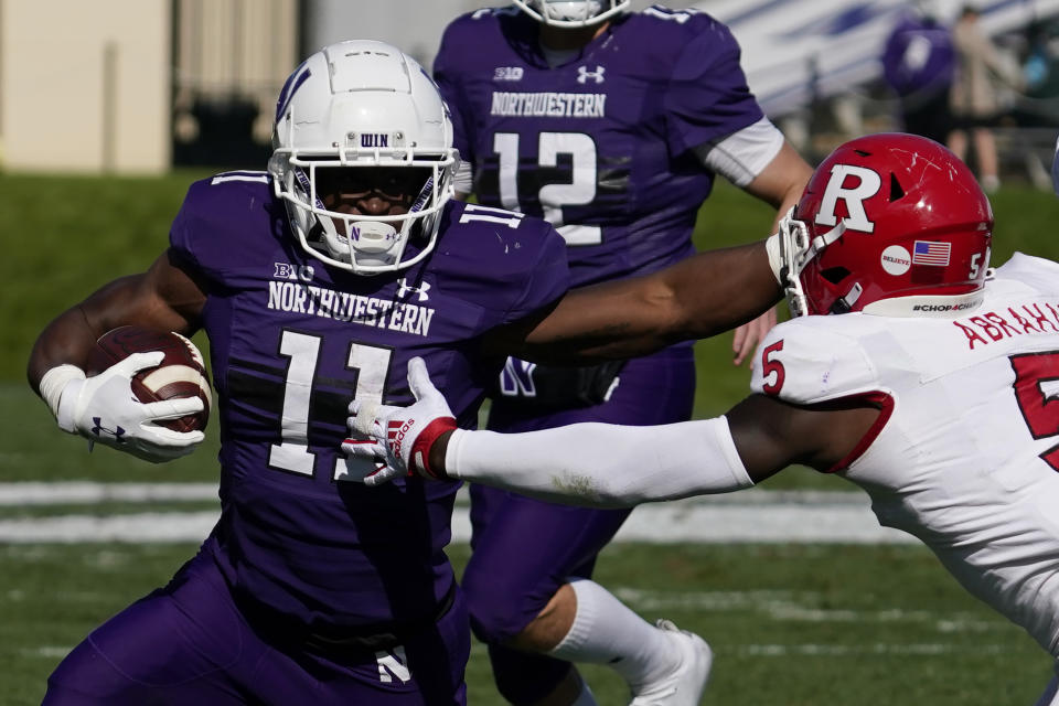 Northwestern Wildcats running back Andrew Clair, left, runs with the ball against Rutgers defensive back Kessawn Abraham during the second half of an NCAA college football game in Evanston, Ill., Saturday, Oct. 16, 2021. Northwestern won 21-7. (AP Photo/Nam Y. Huh)