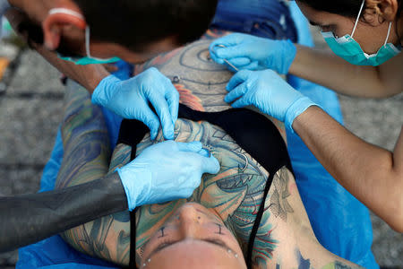 Professional body artist Dino Helvida (L), 27, and his girlfriend Zorana Unkovic (R), 27, prepare Kaitlin, 28, from the United States for body suspension in Zagreb, Croatia June 7, 2016. REUTERS/Antonio Bronic