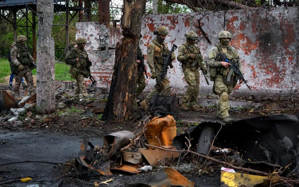 Russian troops walk in a destroyed part of the Illich Iron & Steel Works Metallurgical Plant in Mariupol