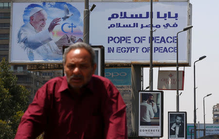 A man rides a bicycle past a billboard ahead of Pope Francis’ visit in Cairo, Egypt April 26, 2017. REUTERS/Amr Abdallah Dalsh