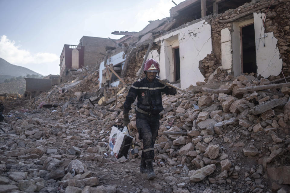 A rescue worker walks through rubble which was caused by the earthquake, in the town of Imi N'tala, outside Marrakech, Morocco, Wednesday, Sept. 13, 2023. An aftershock rattled central Morocco on Wednesday, striking fear into rescue crews at work in High Atlas villages, digging people out from rubble that could slide. (AP Photo/Mosa'ab Elshamy)