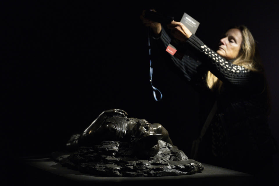 A woman takes a picture of a bronze sculpture by Kehinde Wiley titled "Sleep," at the de Young Museum in San Francisco, Friday, March 24, 2023. The sculpture is part of the "Kehinde Wiley: An Archaeology of Silence," exhibition. (AP Photo/Godofredo A. Vásquez)