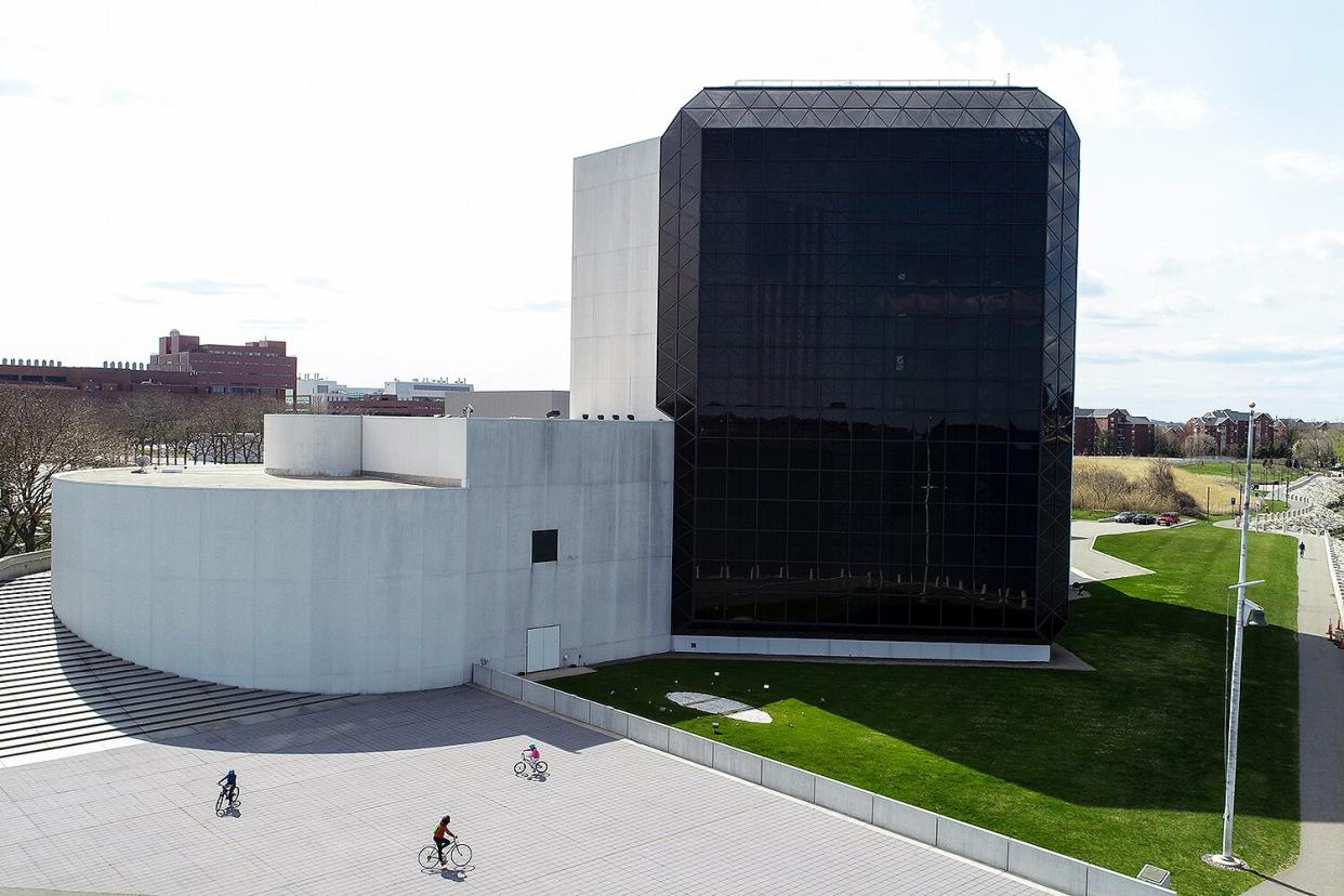 People ride their bikes outside of a closed John F. Kennedy Presidential Library and Museum in Boston on April 17, 2020.