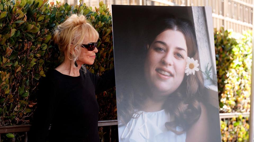 Michelle Phillips looking at a portrait of Mama Cass