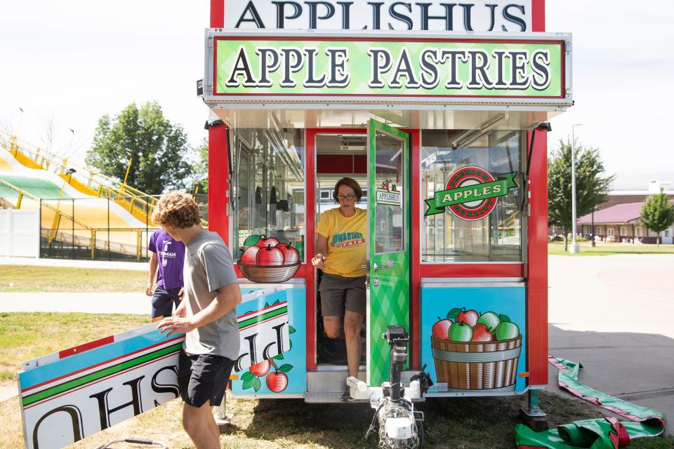 Connie Boesen, center, with the help of Walker Bennett and Shea Stickle, set up one of the Applishus sites at the Iowa State Fairgrounds Saturday, July 30, 2022 in Des Moines.