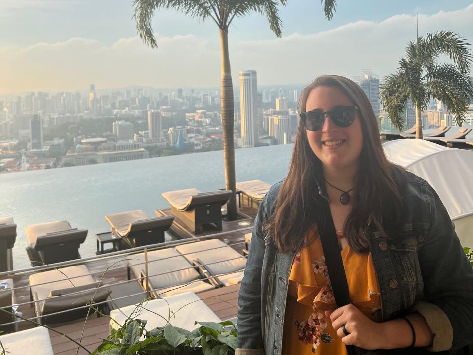 Marina Bay Sands Resort in Singapore — rooftop picture of me with trees, pool, cabanas, and view of the city.