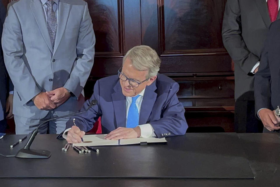 FILE - Ohio Governor Mike DeWine signs an executive order allowing college athletes in Ohio to earn money off their name, image and likeness at the Ohio Statehouse in Columbus, Ohio, in this Monday, June 28, 2021, file photo. The NCAA Board of Directors is expected to greenlight one of the biggest changes in the history of college athletics when it clears the way for athletes to start earning money based on their fame and celebrity without fear of endangering their eligibility or putting their school in jeopardy of violating amateurism rules that have stood for decades. (AP Photo/Farnoush Amiri, File)