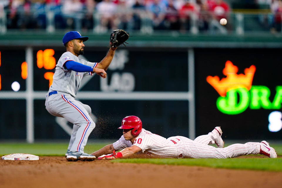 Philadelphia Phillies' J.T. Realmuto beats the throw to Texas Rangers' Marcus Semien at second after a wild pitch by Jon Gray during during the third inning of a baseball game Tuesday, May 3, 2022, in Philadelphia. (AP Photo/Matt Rourke)