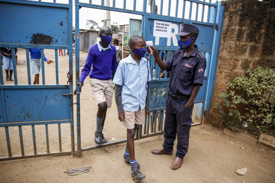 FILE - In this Monday, Oct. 12, 2020 file photo, schoolchildren have their temperature taken as they arrive at the Olympic Primary School in Kibera, one of the capital Nairobi's poorest areas, as schools partially re-opened to allow those students due for examinations which had been postponed to prepare, in Kenya. As schools reopen in some African countries after months of lockdown, relief is matched by anxiety over everything from how to raise tuition fees amid the financial strain wrought by the COVID-19 pandemic to how to protect students in crowded classrooms. (AP Photo/Brian Inganga, File)