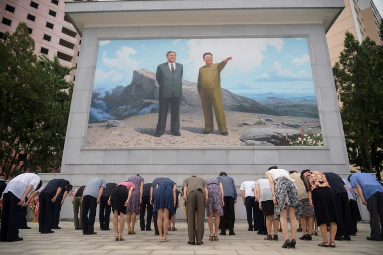 Des Nord-Coréens s'inclinent devant une fresque des dirigeants Kim Il Sung et Kim Jong Il, le 8 juillet 2021 à Pyongyang (KIM Won Jin)