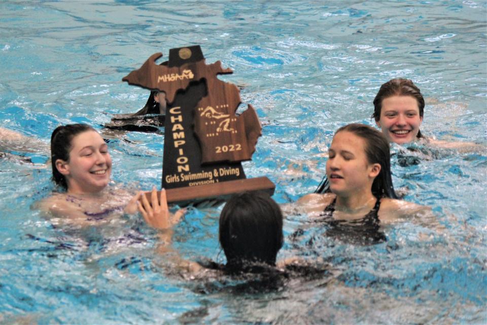 After winning the Division 1 state title, Ann Arbor Pioneer’s Eva Woods, Sophia Guo, Yan Yee Adler and Ursula Ott take the trophy for a swim at Oakland University on Saturday, Nov. 19, 2022.