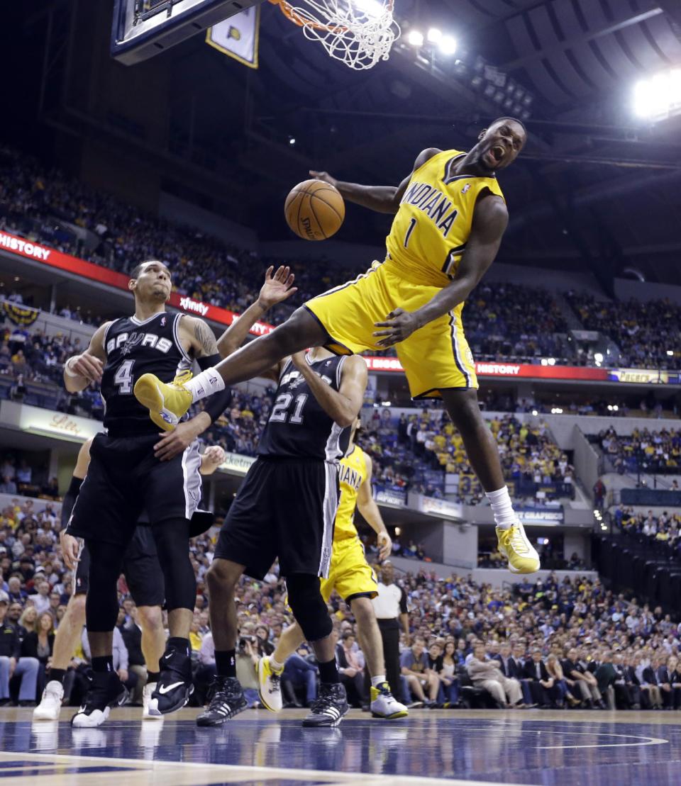 Indiana Pacers guard Lance Stephenson (1) reacts after a slam dunk over San Antonio Spurs guard Danny Green (4) and forward Tim Duncan (21) in the first half of an NBA basketball game in Indianapolis, Monday, March 31, 2014. (AP Photo/Michael Conroy)