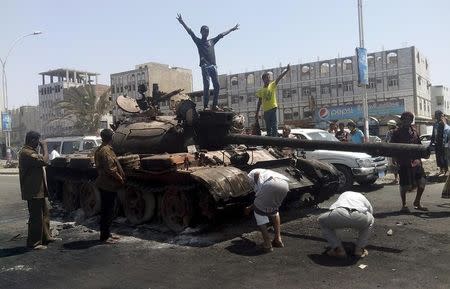 Boys stand on a tank burnt during clashes on a street in Yemen's southern port city of Aden March 29, 2015. REUTERS/Stringer