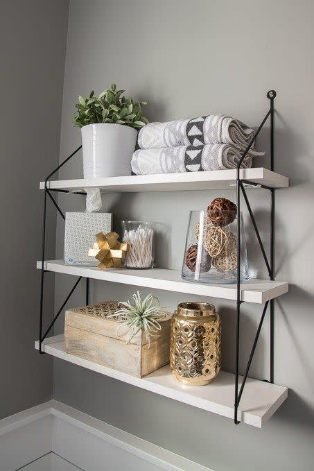 bathroom shelf ideas, three shelves in the bathroom with towels, plants, and jars on top