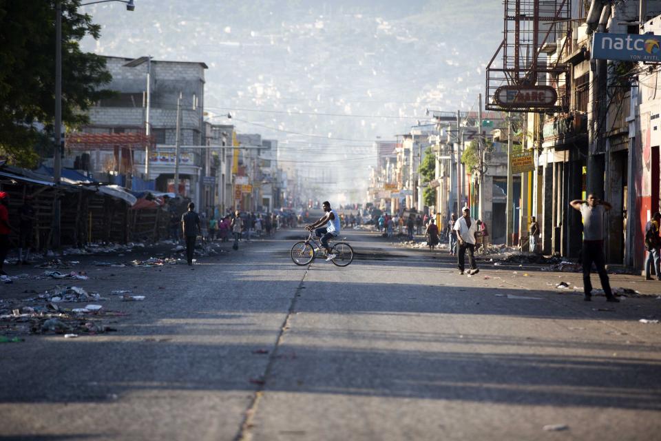 A resident pedals his bicycle in the middle of a usually busy street on the third day of a strike and of countrywide protests over allegations of government corruption, in Port-au-Prince, Haiti, Tuesday, Nov. 20, 2018. Demonstrators are calling for the president to resign for not investigating allegations of corruption in the previous government over a Venezuelan subsidized energy program, Petrocaribe. (AP Photo/Dieu Nalio Chery)