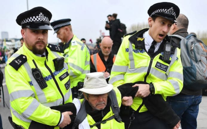 Police officers carry an activist as they remove demonstrators from Waterloo Bridge - Ben Stanstall/AFP