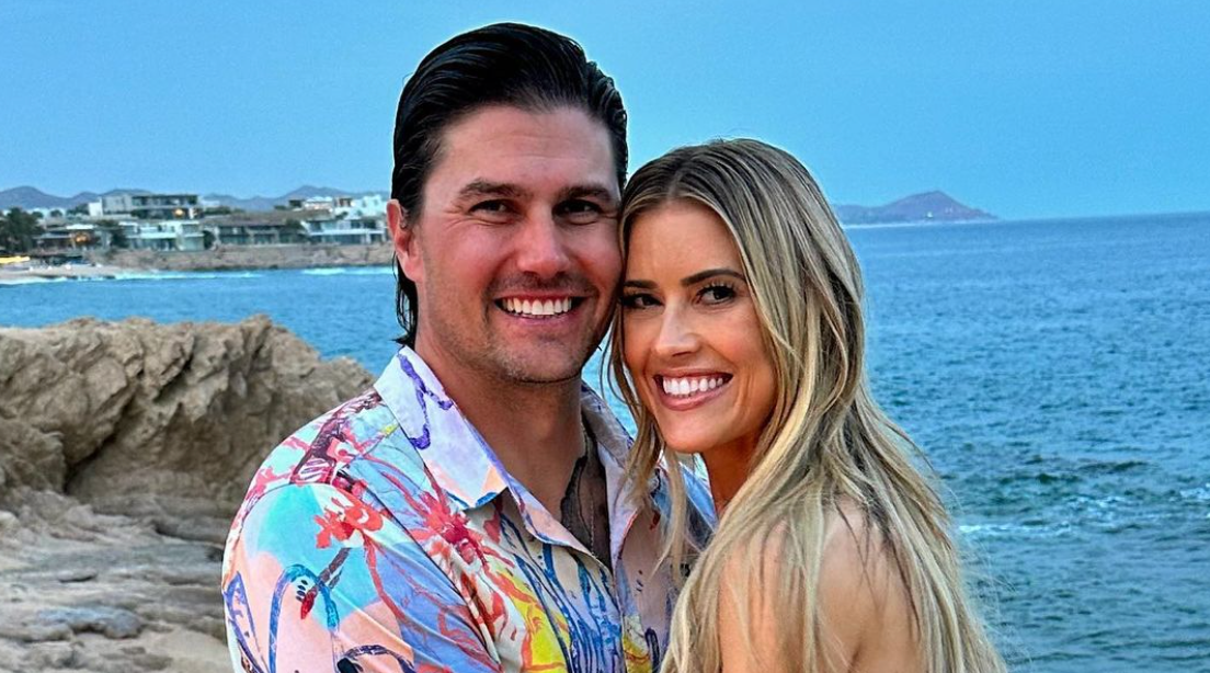 a man and woman posing for a picture on a rocky beach