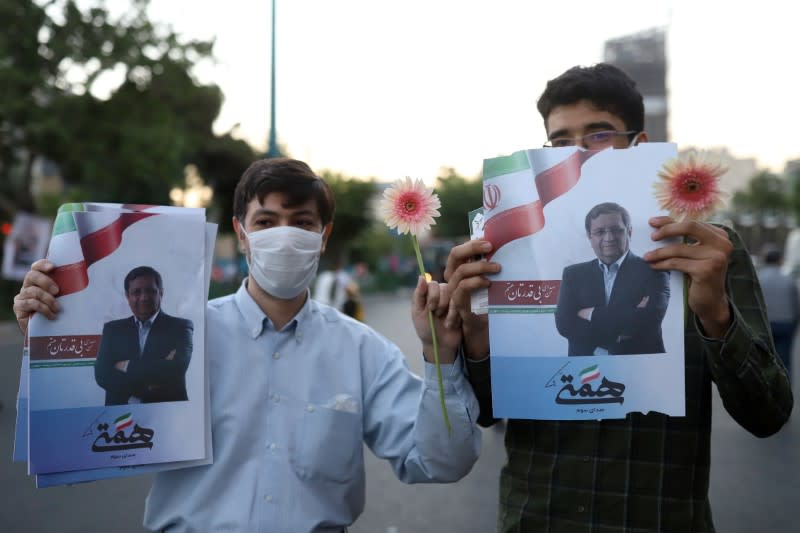 Supporters of presidential candidate Abdolnaser Hemmati hold posters of him in a street in Tehran