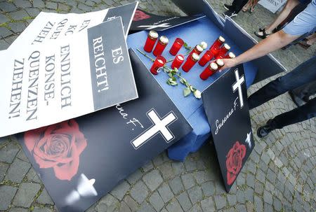 A person places a candle during a demonstration called out by the Anti-immigration party Alternative for Germany (AfD) in Mainz, Germany, June 9, 2018, after a 20-year-old Iraqi man had admitted to the rape and murder of Susanna F., a 14-year-old German girl. Placard reads "Enough, finally draw the consequences". REUTERS/Ralph Orlowski