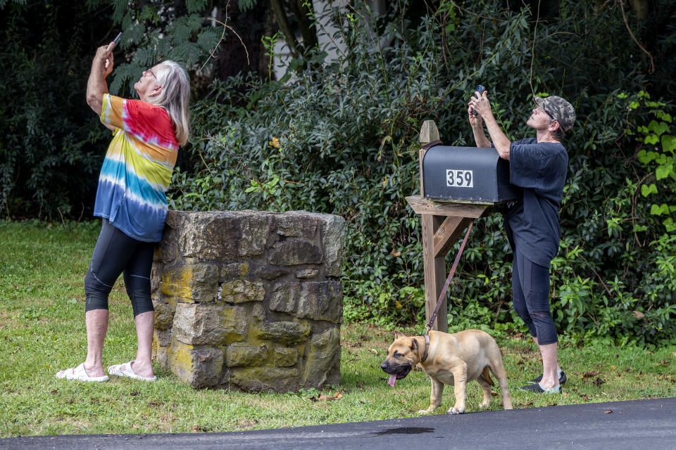 Sisters Pat Howard, left, and Debbie Shaw, with her dog Bubba, watch news helicopters in the air over their neighborhood in Nantmeal Village Monday, Sept.11, 2023 as the search for escaped convict Danelo Cavalcante continues in northern Chester County. This is is the area where his stolen van was located on Sunday. (Tom Gralish/The Philadelphia Inquirer via AP)