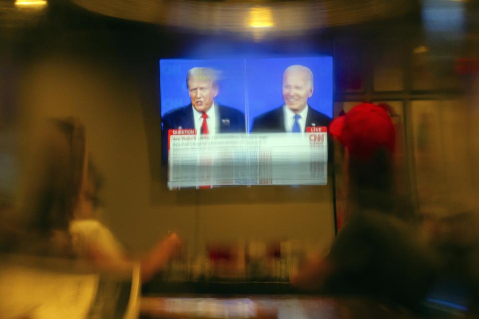 Vistos a través de un vaso de cerveza, clientes de un bar siguen el debate electoral entre el presidente de Estados Unidos, Joe Biden, y el candidato republicano, el expresidente Donald Trump, en la Old Louisville Tavern, el 27 de junio de 2024, en Louisville, Kentucky. (AP Foto/Jon Cherry)