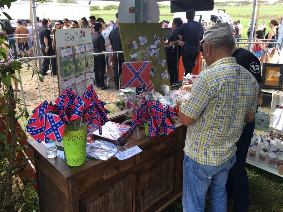 <span class="caption">Confederate iconography sold on miniature flags, buttons and mousepads at the 2019 ‘Festa Confederada.’</span> <span class="attribution"><span class="source">Jordan Brasher</span></span>