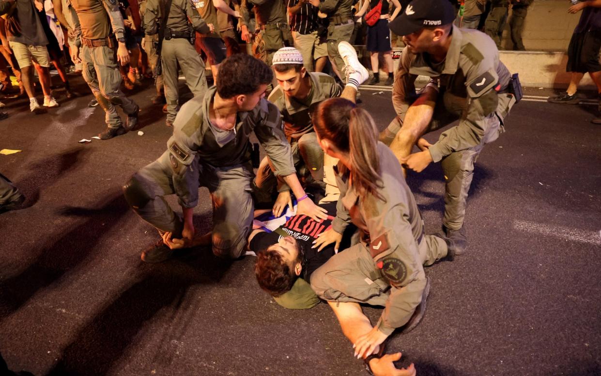 Israeli Police officers detain a protester during clashes in Tel Aviv