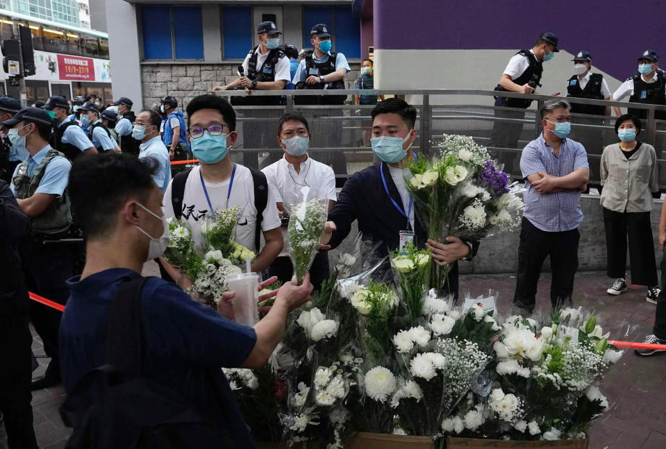 People place flowers outside the Prince Edward subway station in Hong Kong Monday, Aug. 31, 2020. Aug. 31 is the first anniversary of police raid on Prince Edward subway station which resulted in widespread images of police beating people and drenching them with pepper spray in subway carriages. (AP Photo/Vincent Yu)